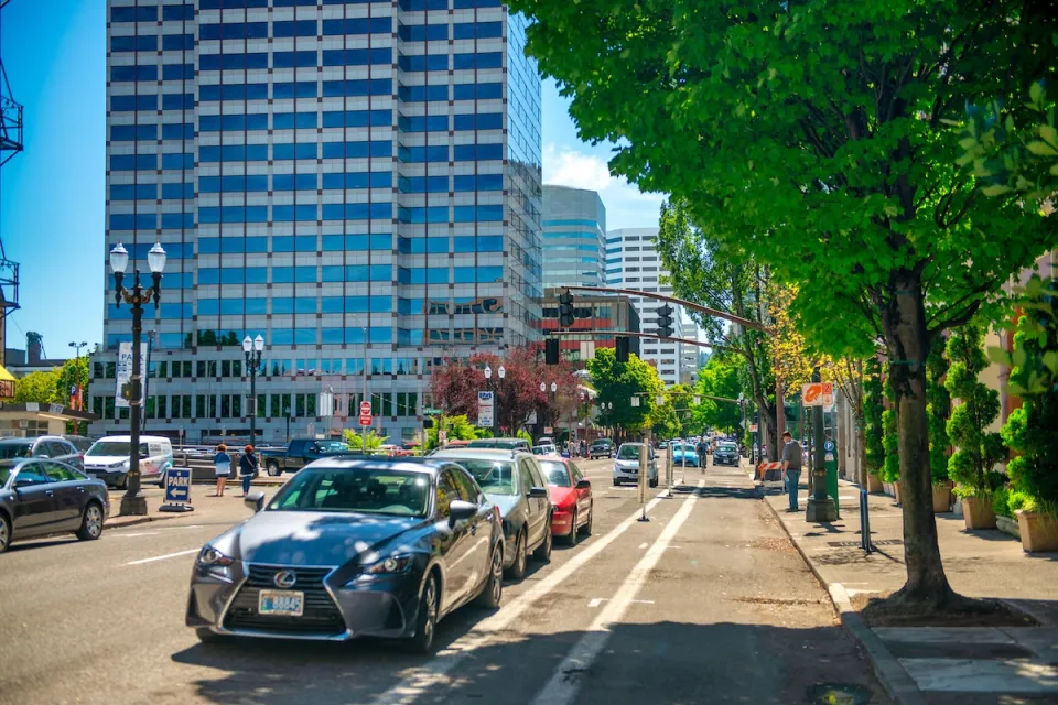 Street with parking protected bike lane and parked cars in downtown Portland, Oregon.